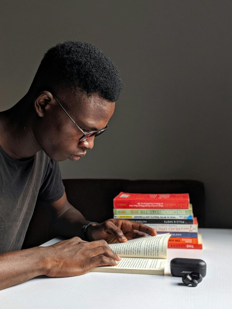 Young man studying intently with books in library setting.